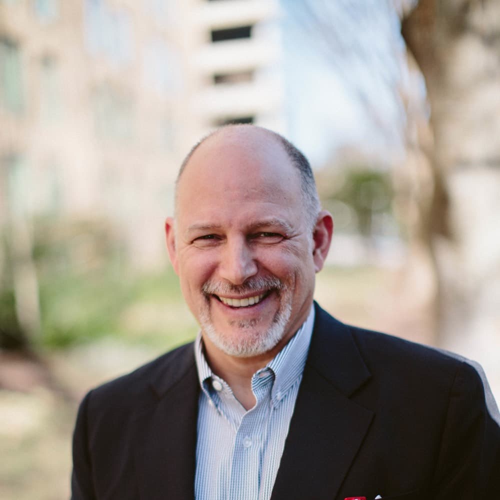 Greg Zlevor smiling in a dark jacket