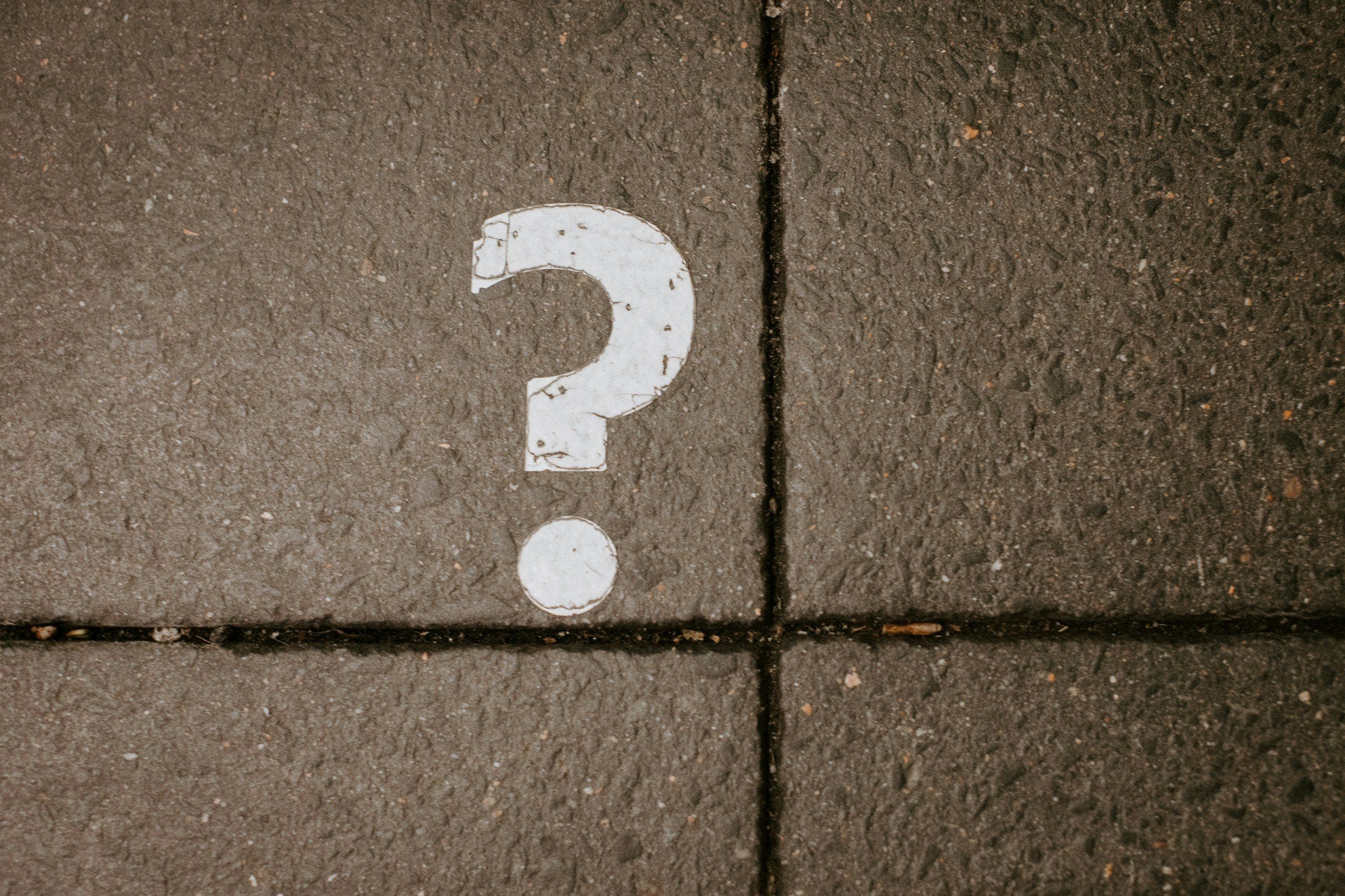 A white question mark painted on a paving stone