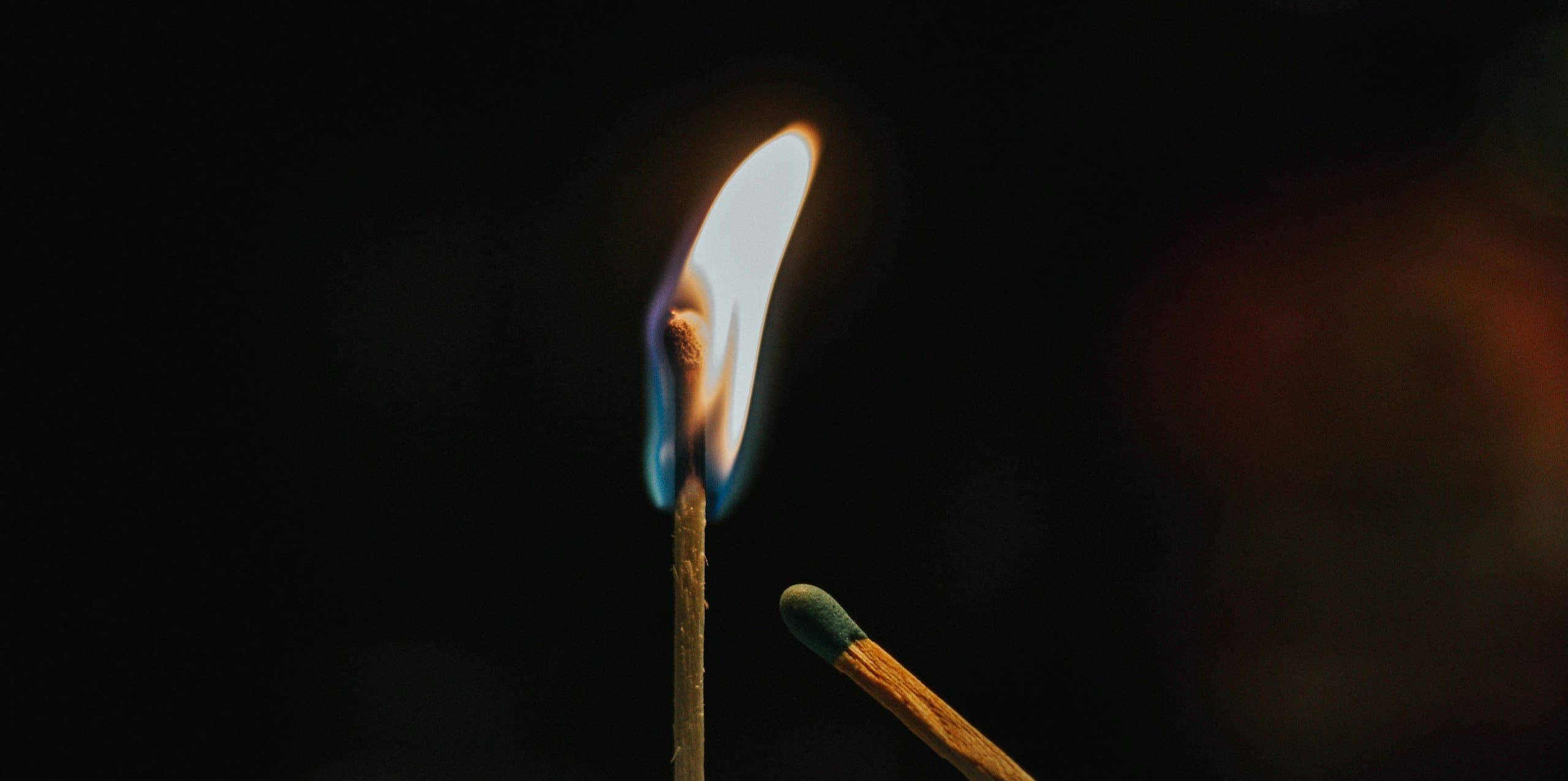 A burning match standing beside an unlit one