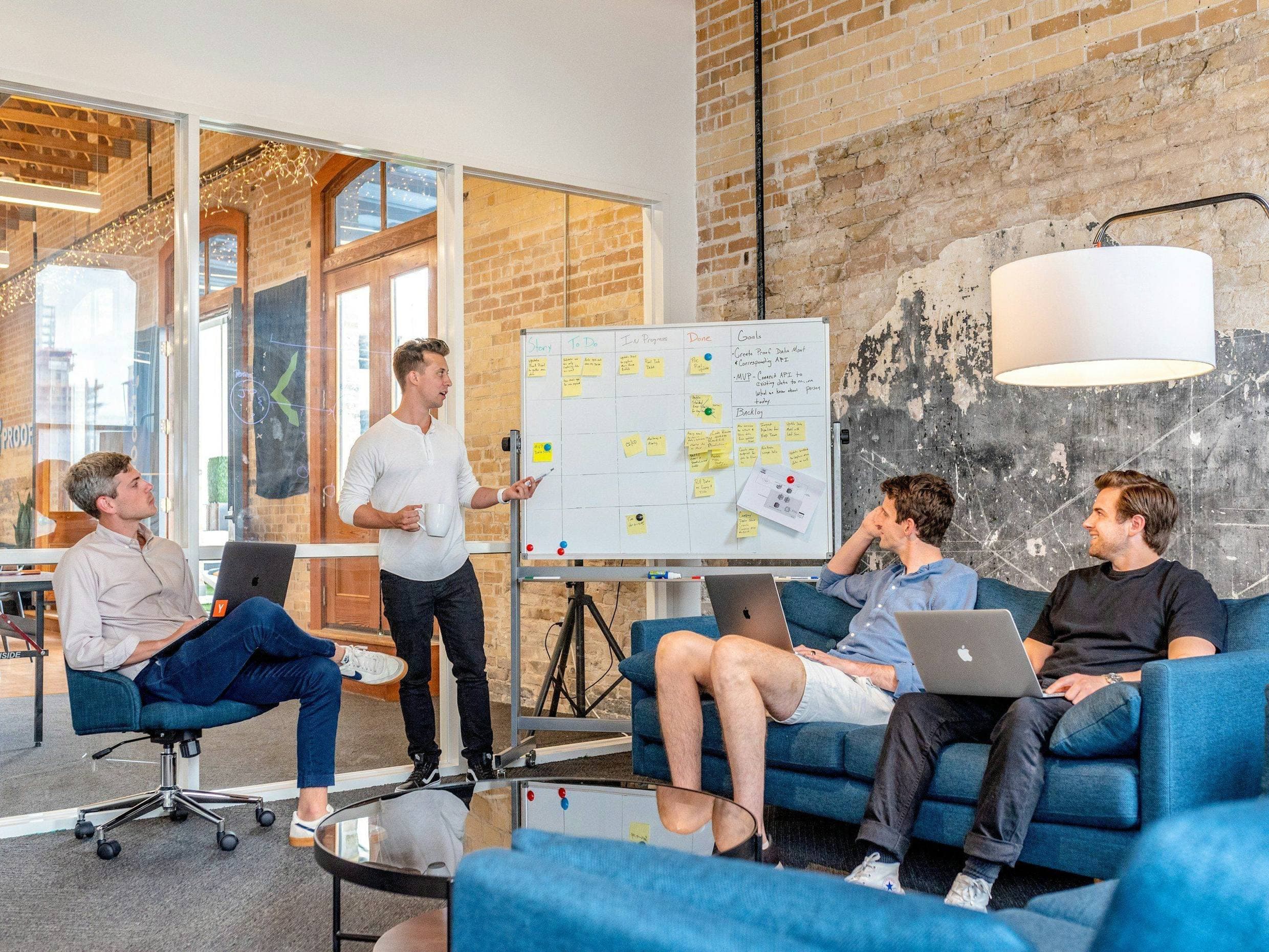 A team on sofas watching a colleague present at a whiteboard