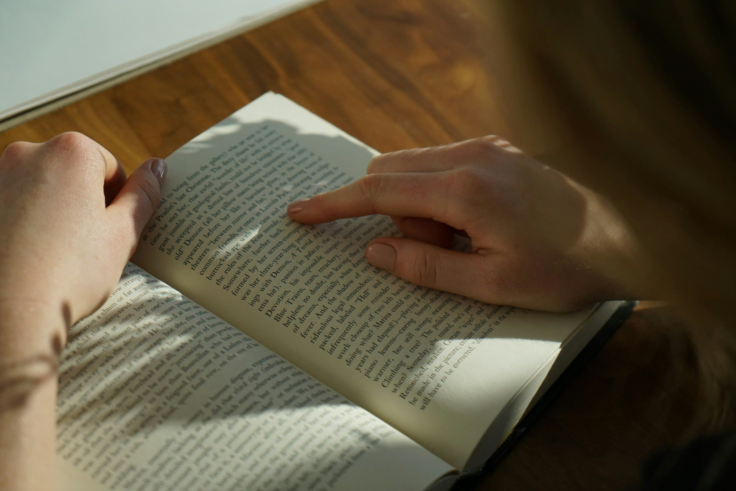 An open book on a wooden table in sunlight