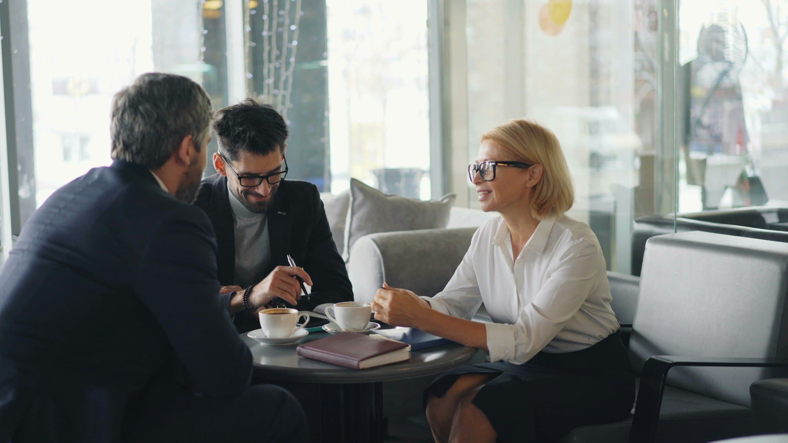 Two colleagues listening as a third speaks over coffee